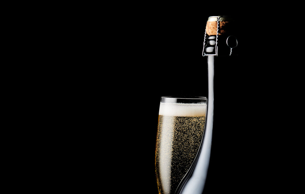 t might be the end of 2020, but dont pop the cork just yet. A glass of champagne next to a corked bottle on a black background. Captured by Mark Wildsmith Sheffield based food photographer
