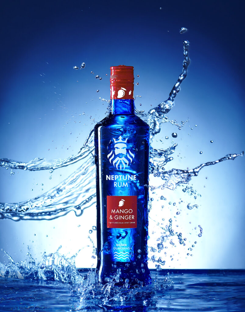 Mango & ginger rum made by Neptune rum in Sheffield. Water crashing over the vivid blue bottle. Photographed by Mark Wildsmith from Wildsmith Photography in Sheffield.